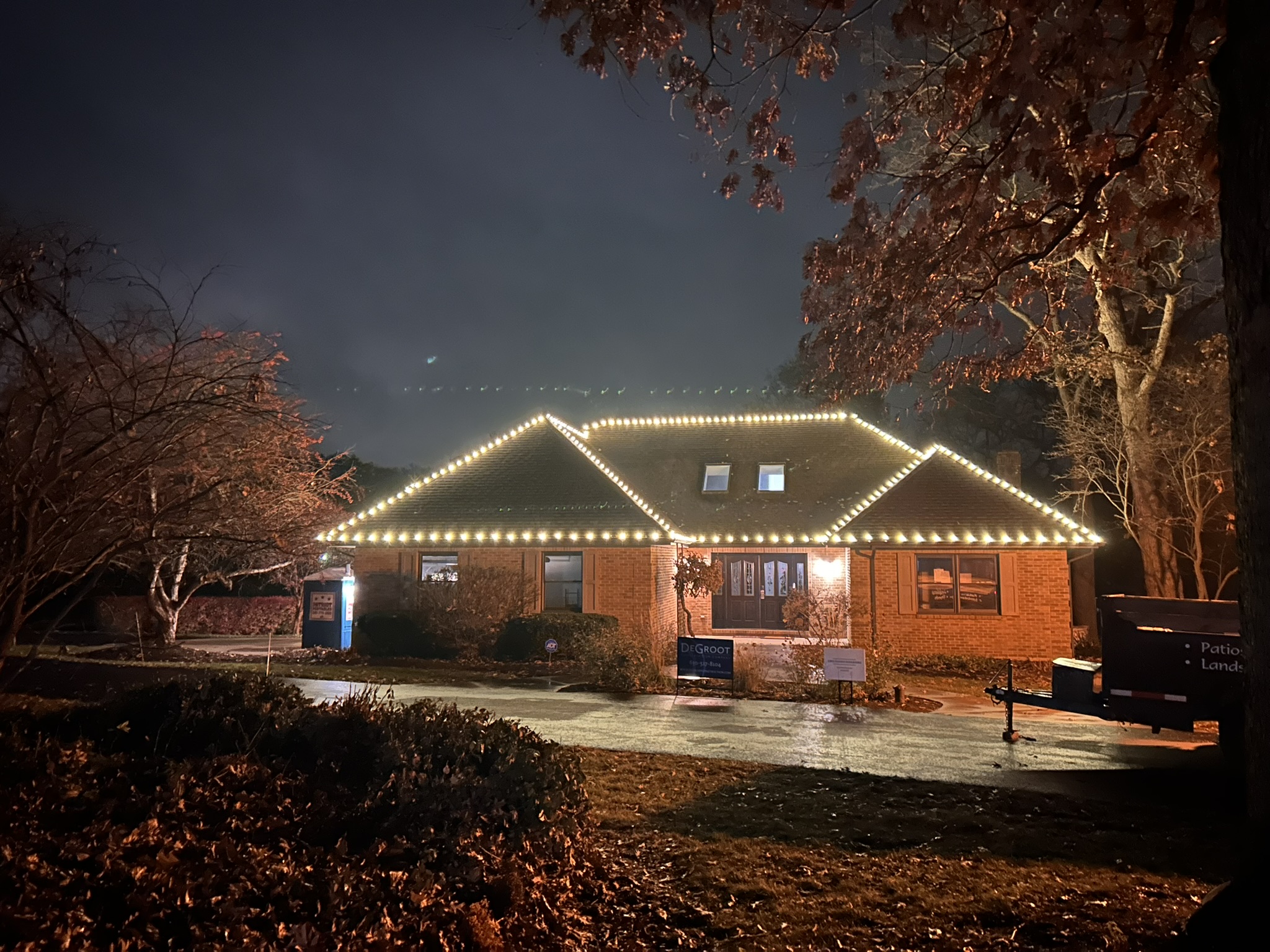 Brick ranch home outlined in warm white roofline lights on a foggy night